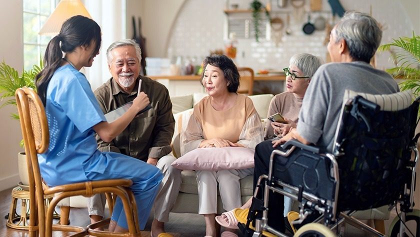 A group of elderly patients speaking with a healthcare worker