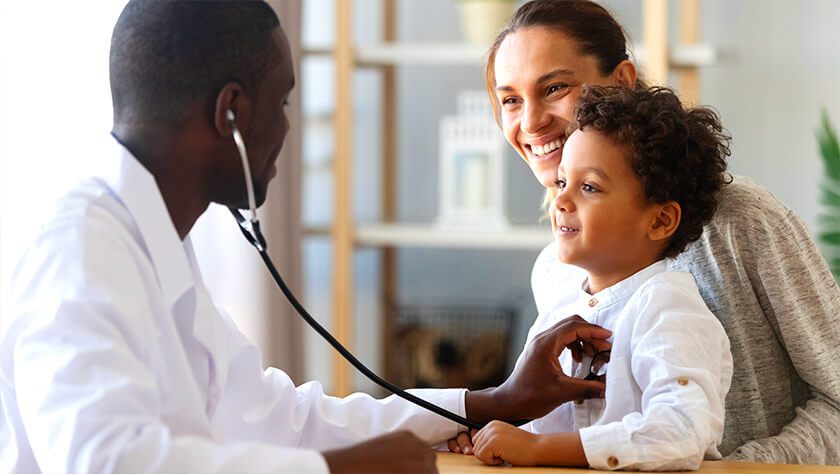 Doctor listening to heard beat of young child on mother's lap