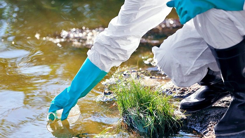 A researcher gathering samples from a natural water source in a beaker
