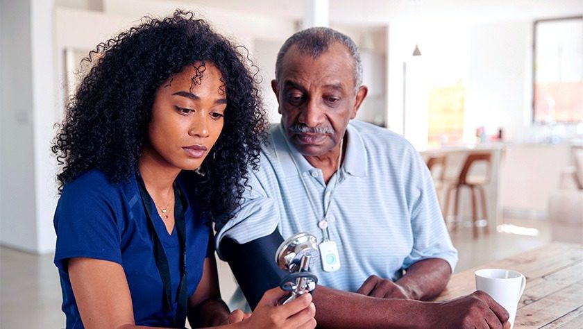 An African American nurse taking the blood pressure of an elderly African American man